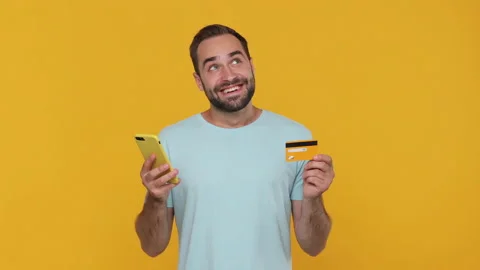 Happy dreamful young man in basic casual blue tshirt holding hand credit bank 動画素材 148291221