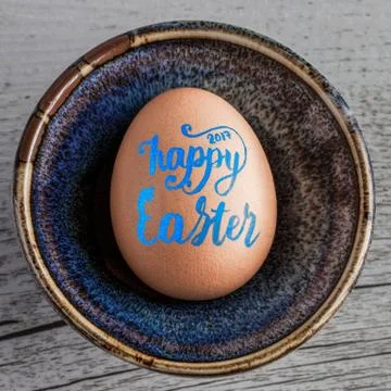 Happy Easter 2017 Handwritten in blue lettering on egg closeup. Square image. Stock Photos