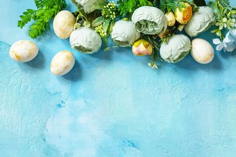 Happy Easter background. Spring flowers and Easter eggs on a concrete blue ba Stock Photos
