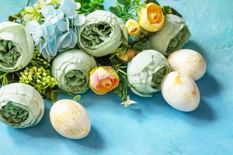 Happy Easter background. Spring flowers and Easter eggs on a concrete blue ba Stock Photos