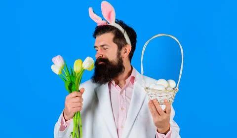 Happy easter. Bearded man with bunny ears with basket eggs and bouquet of tul Foto stock
