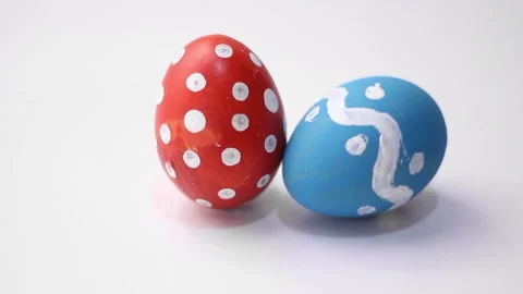 Happy Easter. Blue egg with dotted and zigzag pattern spins and hits red egg Stock Footage 269545900