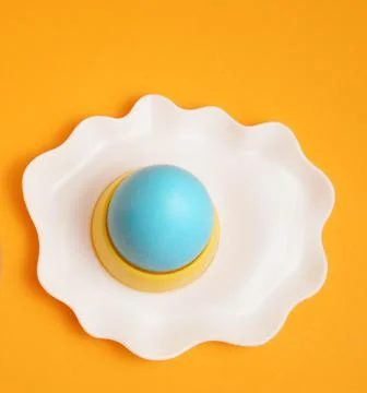 Happy Easter. Blue egg on an egg stand. Breakfast. Orange background. Stock Photos