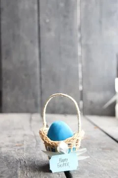 Happy easter. Blue egg on rustic table and a basket with a tag Stock Photos
