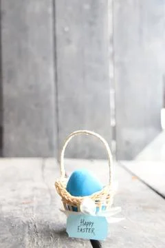 Happy easter. Blue egg on rustic table and a basket with a tag. Stock Photos