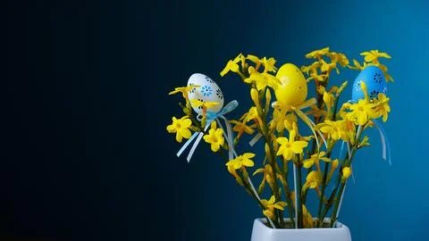 Happy Easter. Bouquet of spring yellow flowers on blue background with easter Stock Photos