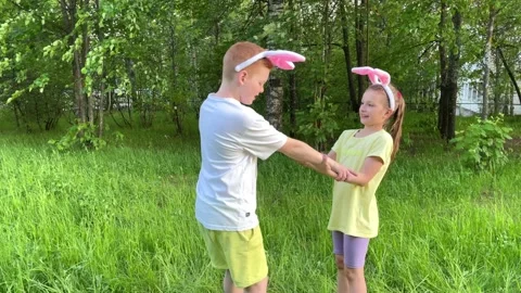 Happy easter, boy and girl in forgetful bunny ears have fun in nature and spin Stock Footage 197060404
