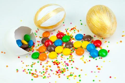 Happy Easter. Broken Easter egg with multi-colored candy decorations. on wh.. Stock Photos