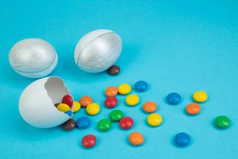 Happy Easter. Broken Easter egg with multi-colored candy decorations on blu.. Stock Photos
