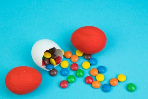 Happy Easter. Broken Easter egg with multi-colored candy decorations on blu.. Stock Photos