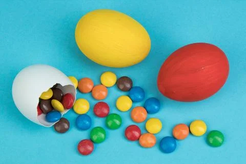 Happy Easter. Broken Easter egg with multi-colored candy decorations on blue  Stock Photos
