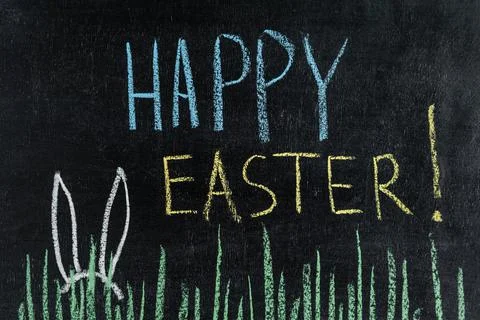 Happy Easter on a chalk board, grass and Easter bunny ears. Stock Photos