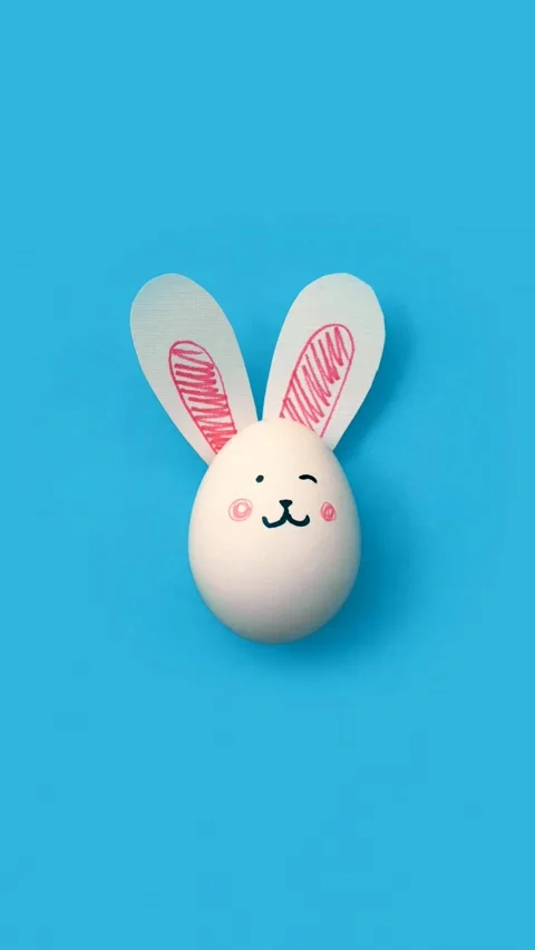Happy Easter. Chicken egg with cute rabbit face and bunny ears on light blue Video stock 304716937