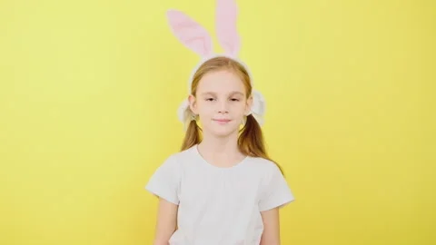 Happy easter. A child in the ears of a hare on yellow background Stock Footage 277621187