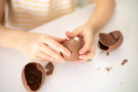 Happy Easter. Close-up of children's hands open breaking chocolate egg with Stock Photos