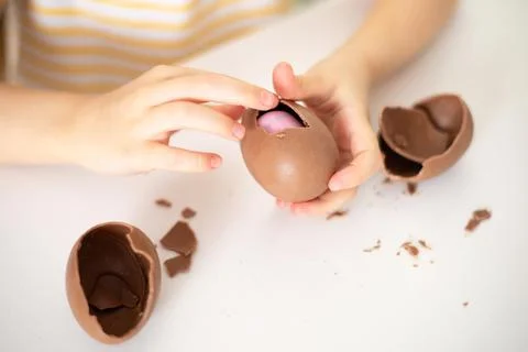 Happy Easter. Close-up of children's hands open breaking chocolate egg with Stock Photos