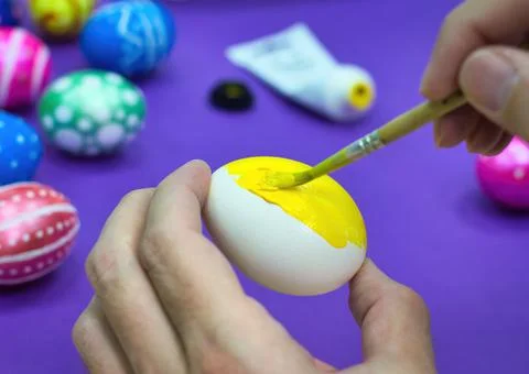 Happy Easter Close Up. White man painting a yellow Easter egg with a brush Stock Photos