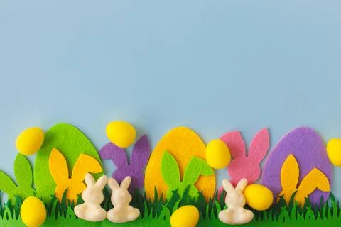 Happy Easter! Colorful Easter bunnies, eggs in grass on blue background, to.. Stock Photos