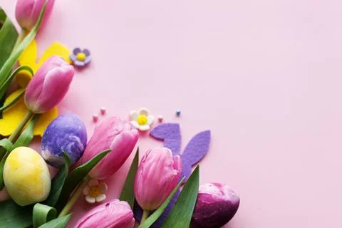 Happy Easter! Colorful easter eggs with bunny ears and pink tulips flat lay.. Stock Photos