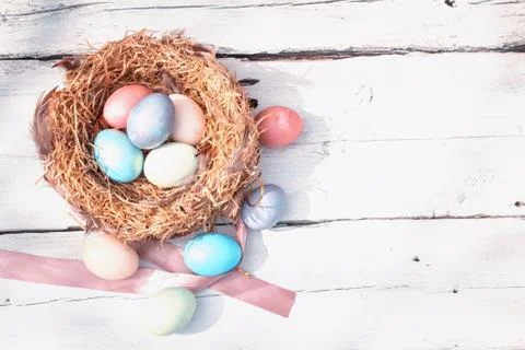Happy Easter. Colorful Easters eggs in a nest with feathers on the wooden Stock Photos