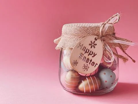 Happy Easter. Colourful painted easter eggs in glass jar on pink background,  Stock Photos