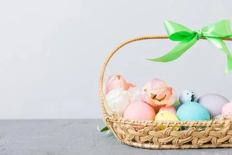 Happy Easter composition. Easter eggs in basket on colored table with yellow  Stock Photos