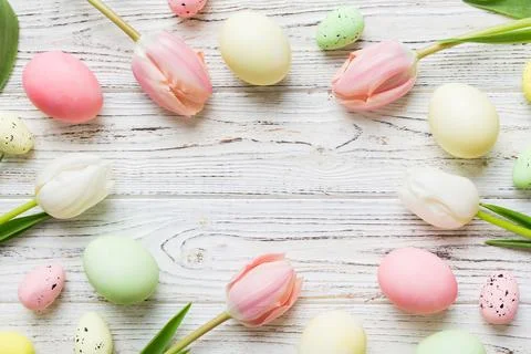 Happy Easter composition. Easter eggs on colored table with yellow Tulips. Na Stock Photos