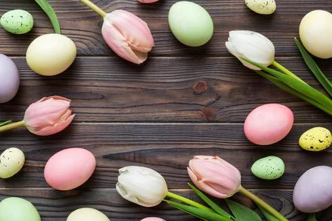 Happy Easter composition. Easter eggs on colored table with yellow Tulips. Na Stock Photos
