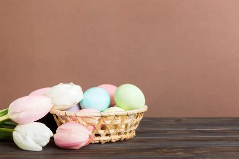 Happy Easter composition. Easter eggs in basket on colored table with yello.. Stock Photos