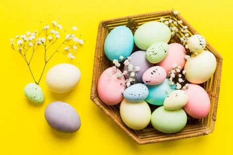 Happy Easter composition. Easter eggs in basket on colored table with gypso.. 库存照片