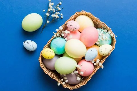 Happy Easter composition. Easter eggs in basket on colored table with gypso.. 스톡 사진