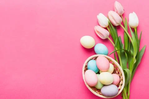 Happy Easter composition. Easter eggs in basket on colored table with yellow  库存照片