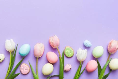 Happy Easter composition. Easter eggs on colored table with yellow Tulips. .. 库存照片