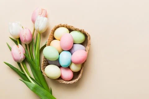 Happy Easter composition. Easter eggs in basket on colored table with yellow  库存照片