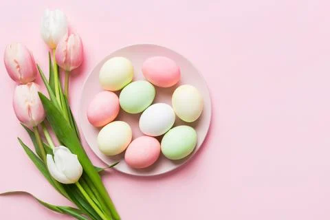 Happy Easter composition. Easter eggs in basket on colored table with yellow  Stock Photos