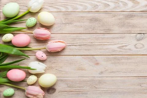 Happy Easter composition. Easter eggs on colored table with yellow Tulips. Na 库存照片