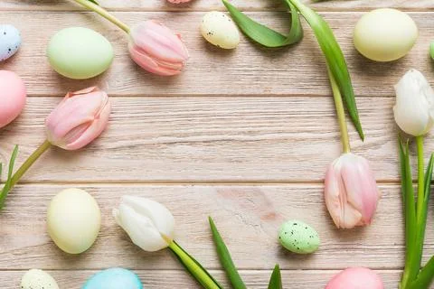 Happy Easter composition. Easter eggs on colored table with yellow Tulips. Na 库存照片