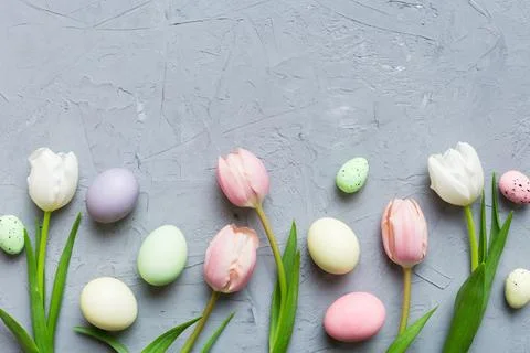 Happy Easter composition. Easter eggs on colored table with yellow Tulips. Na 库存照片
