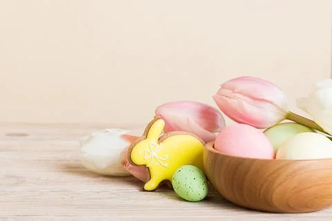 Happy Easter composition. Easter eggs in basket on colored table with yellow  库存照片