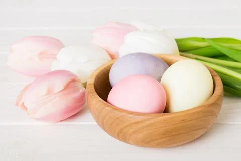 Happy Easter composition. Easter eggs in basket on colored table with yellow  Stock Photos