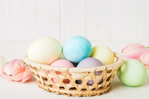 Happy Easter composition. Easter eggs in basket on colored table with yellow  库存照片