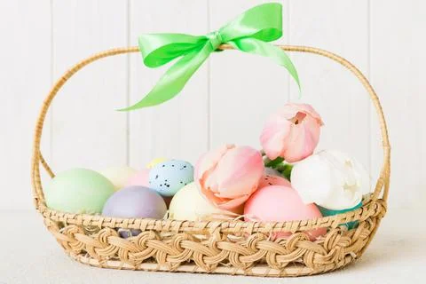 Happy Easter composition. Easter eggs in basket on colored table with yellow  Stock Photos