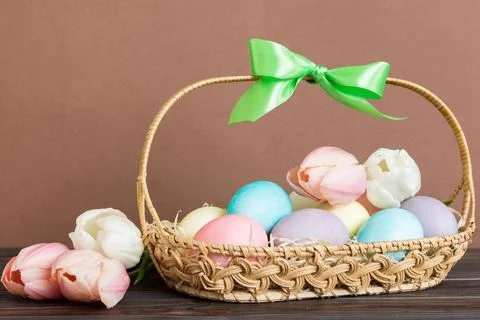 Happy Easter composition. Easter eggs in basket on colored table with yello.. Stock Photos