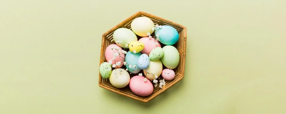 Happy Easter composition. Easter eggs in basket on colored table with gypsoph Stock Photos