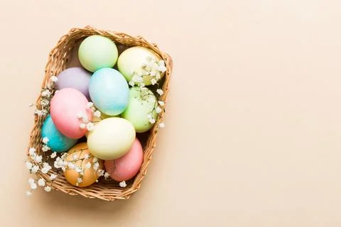 Happy Easter composition. Easter eggs in basket on colored table with gypsoph Stock Photos