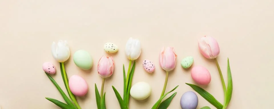 Happy Easter composition. Easter eggs on colored table with yellow Tulips. .. 库存照片