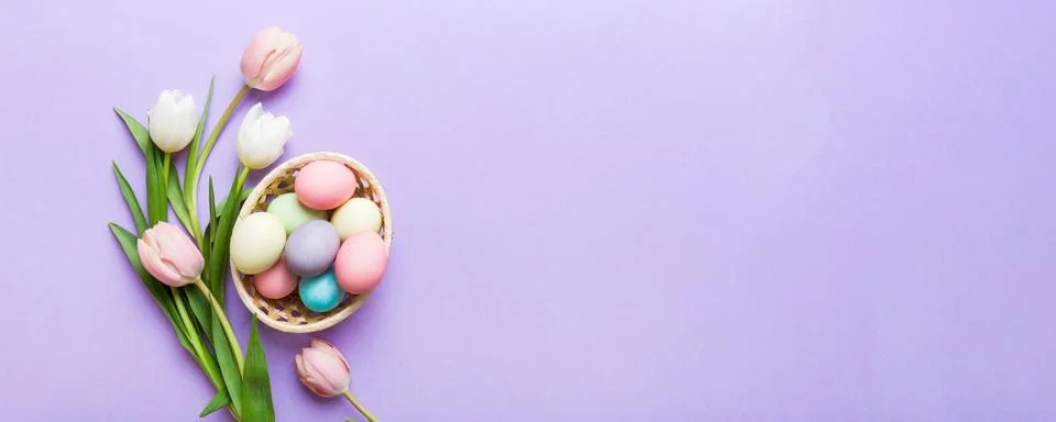 Happy Easter composition. Easter eggs in basket on colored table with yello.. Stock Photos