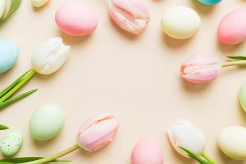 Happy Easter composition. Easter eggs on colored table with yellow Tulips. .. Stock Photos