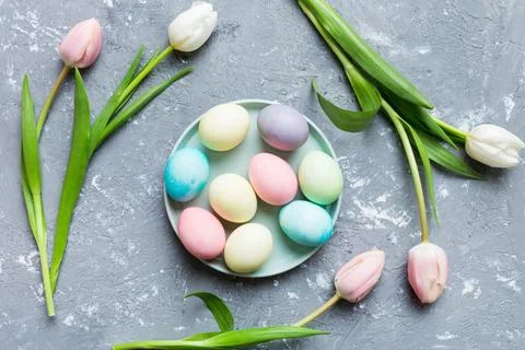 Happy Easter composition. Easter eggs in basket on colored table with yellow  Stock Photos