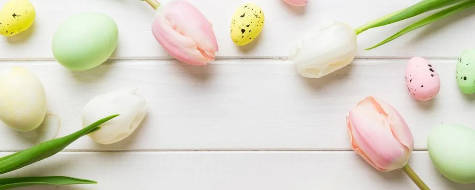 Happy Easter composition. Easter eggs on colored table with yellow Tulips. .. Stock Photos